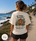 Woman wearing a t-shirt with a Bible verse and lion of Judah by the ocean.