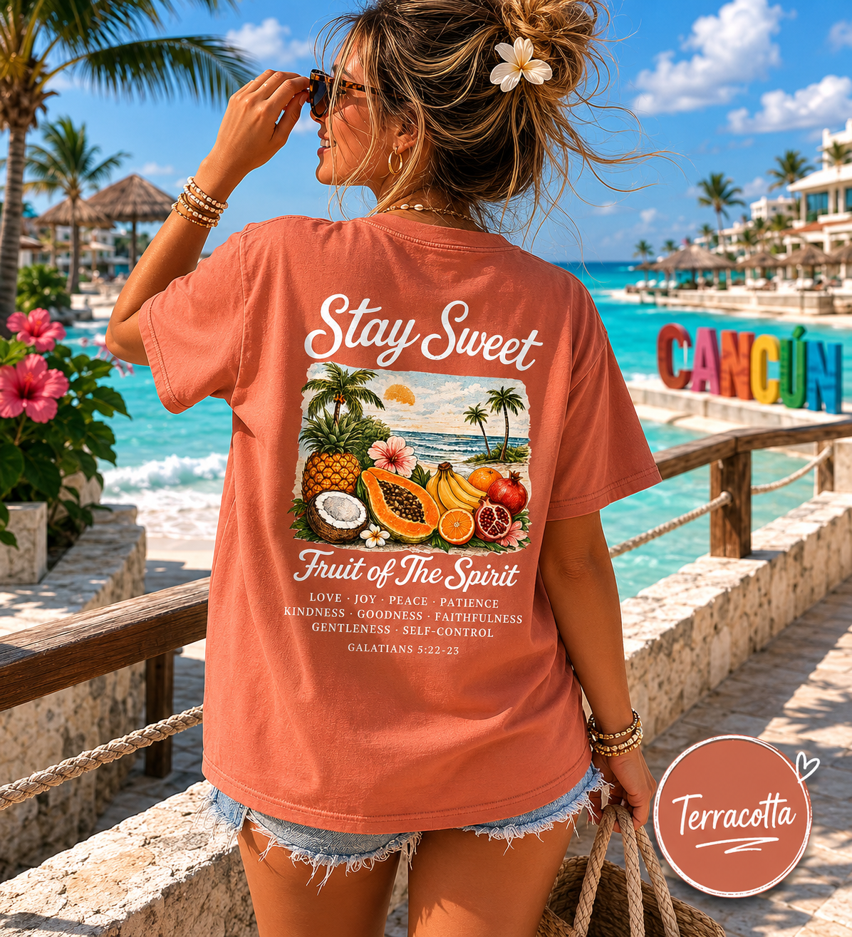 Woman wearing a 'Stay Sweet Fruit of the Spirit' t-shirt by a tropical beach with 'Cancun' sign.