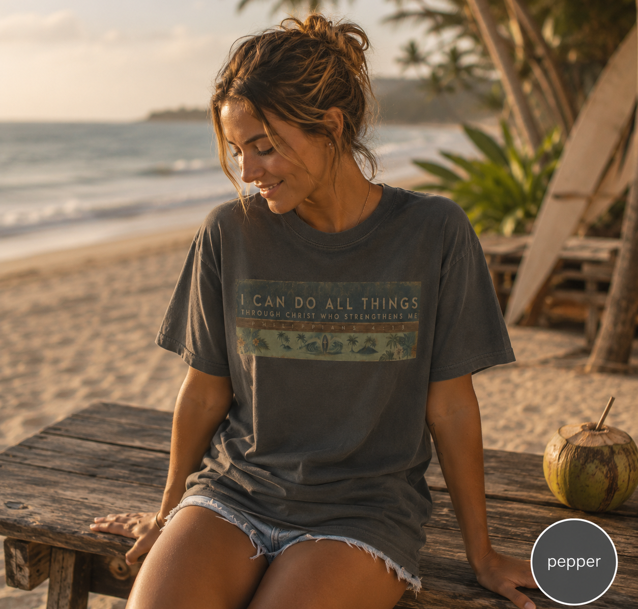 Woman sitting on a wooden bench by the beach wearing surf t-shirt with a motivational quote.